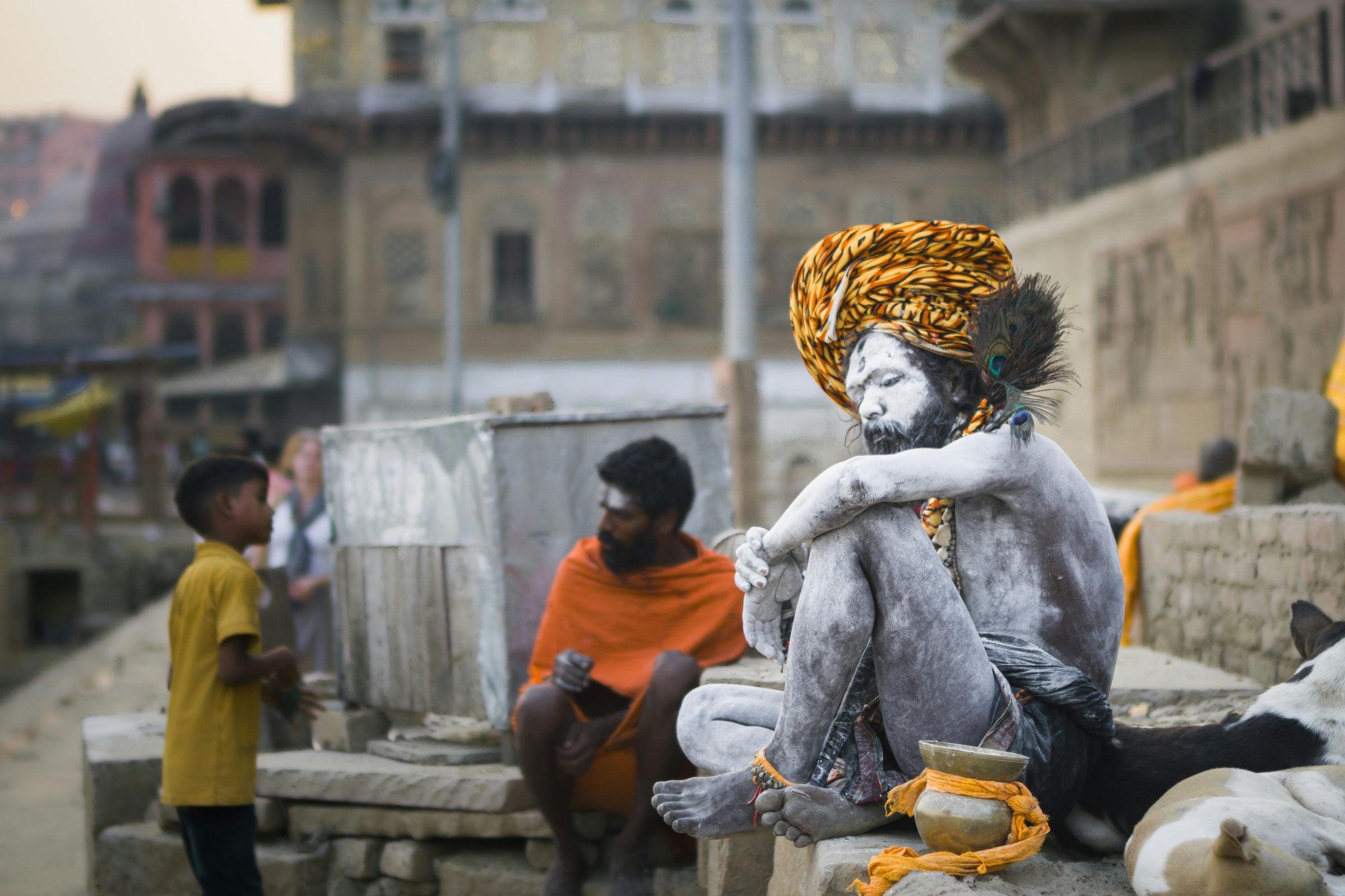 A sadhu in a marigold turban seated on the ghat steps beside a boy